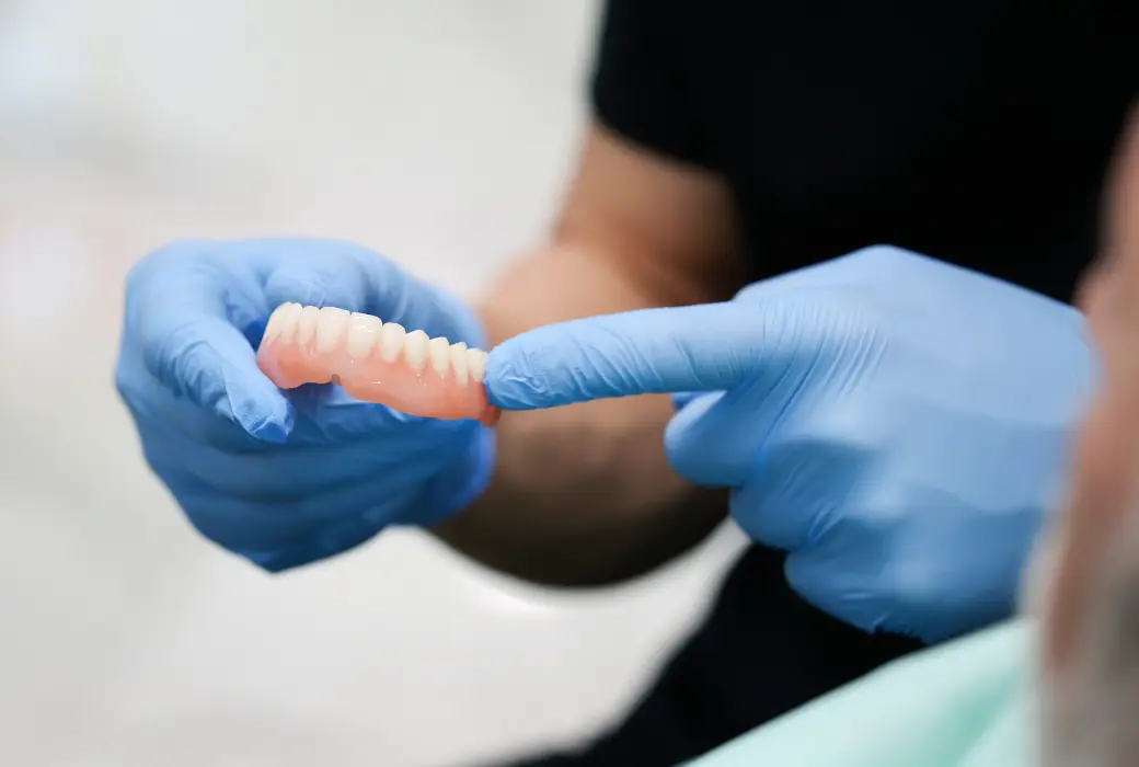 El odontólogo sostiene una prótesis dental removible superior para paciente edéntulo en Belgrano Studio Dental